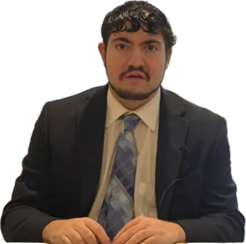 Jon Elias in a suit and tie at his desk, looking right at you